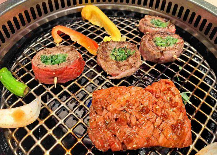 Premium wagyu beef and vegetables being grilled at a yakiniku restaurant in Kyoto.